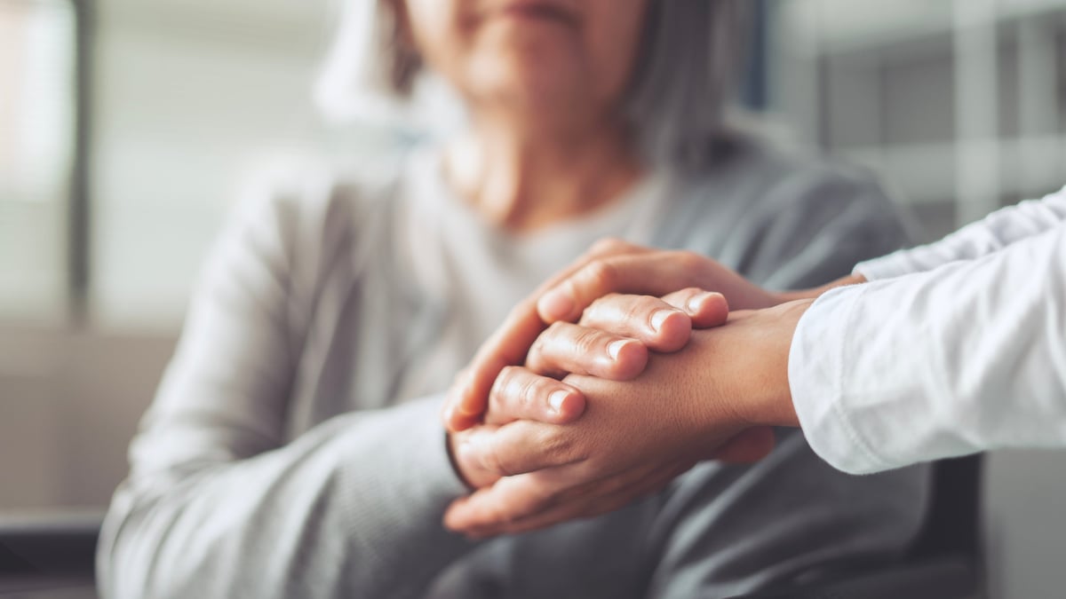 Hands holding old woman's hands in care and comfort